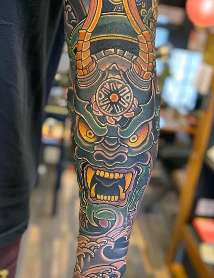 Japanese mask tattoo example showing neotraditional color and sleeve-style placement